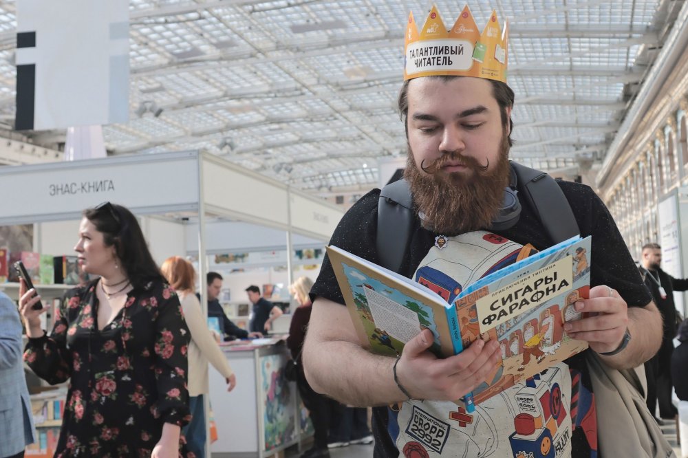 Покупатель в короне на книжной ярмарке держит комиксы