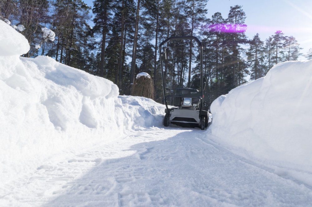 Крупный план, снегоуборщик аккуратно очищает дорожку от снега.