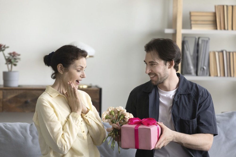 Взрослый сын дарит подарок маме.