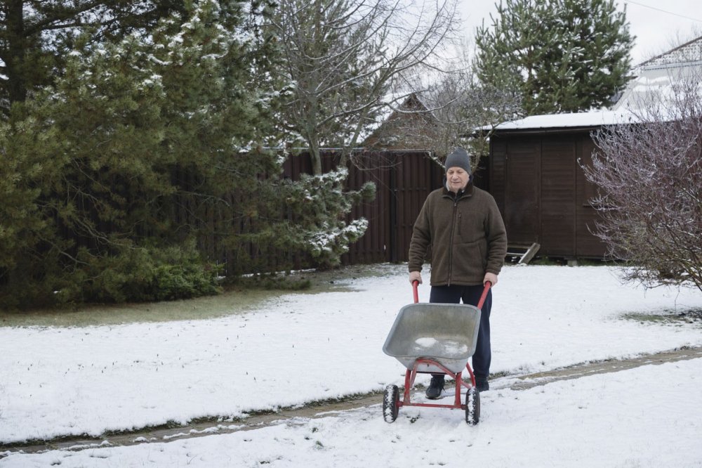 Мужчина работает на дачном участке ранней весной.