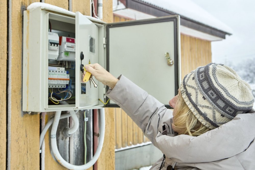 Женщина проверяет счетчик электроэнергии на даче.