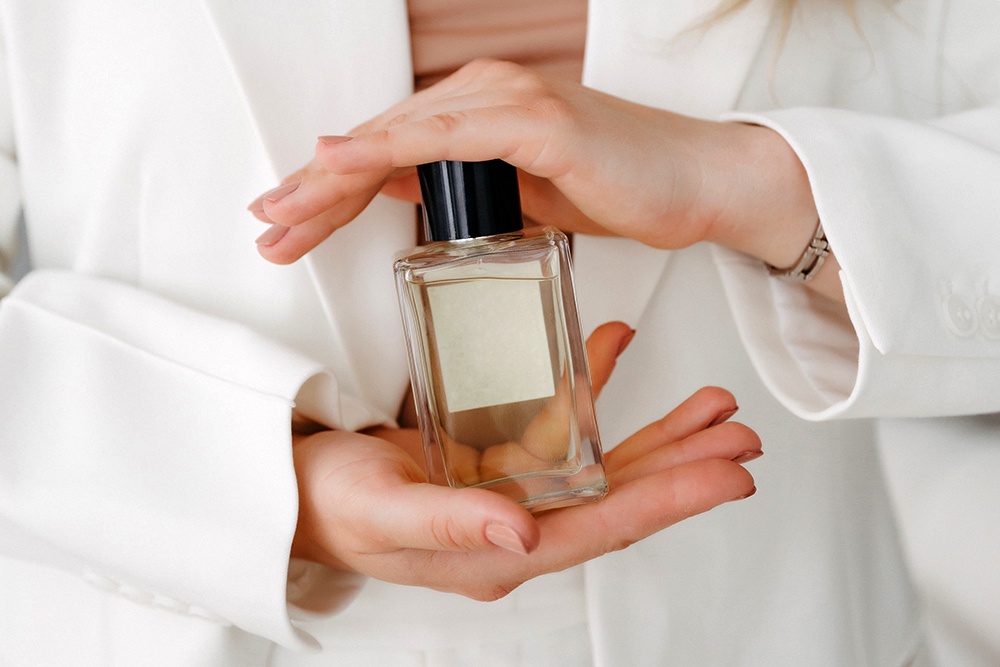 Девушка держит флакон духов