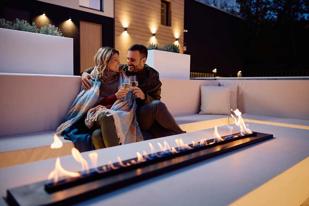 Влюбленные сидят перед газовым камином на открытой веранде