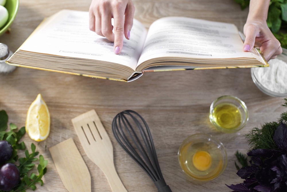 Девушка держит в руках кулинарную книгу