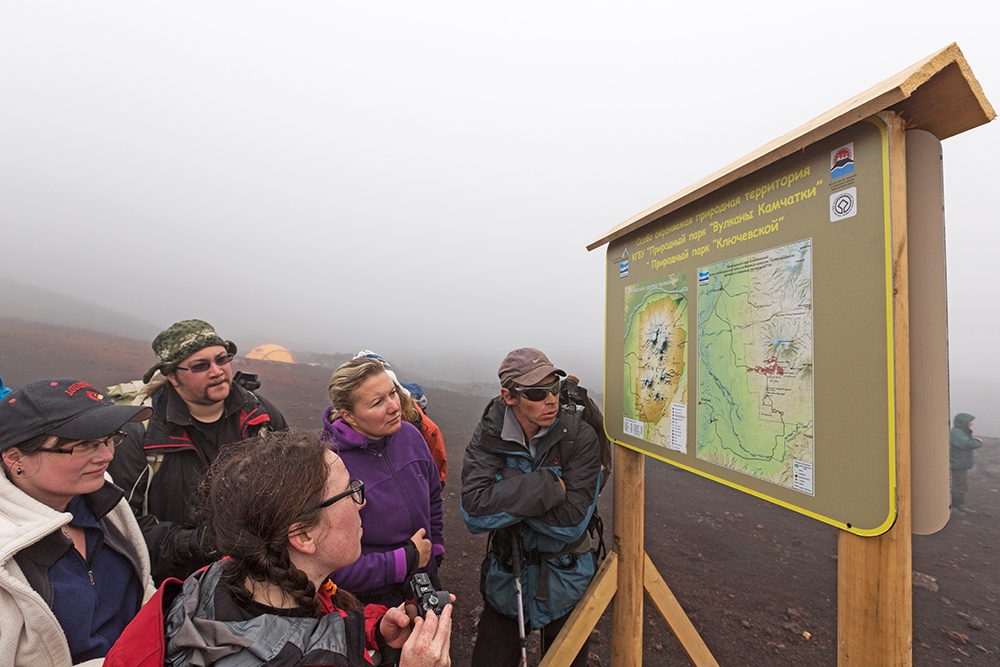Туристы изучают карту Ключевской группы вулканов 