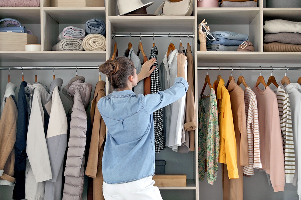 женщина развешивает одежду в гардеробной