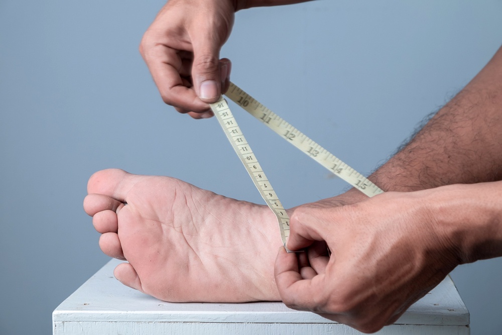 Мужчина измеряет стопу