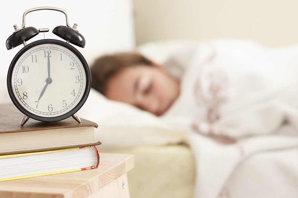 Будильник на фоне спящей девушки
