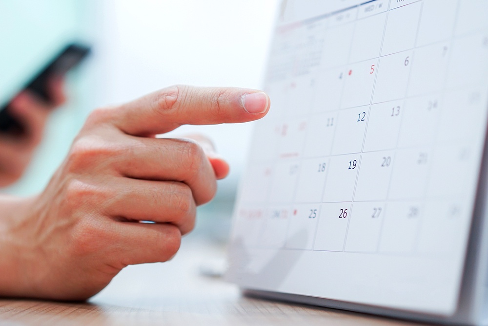 палец человека показывает на бумажный календарь