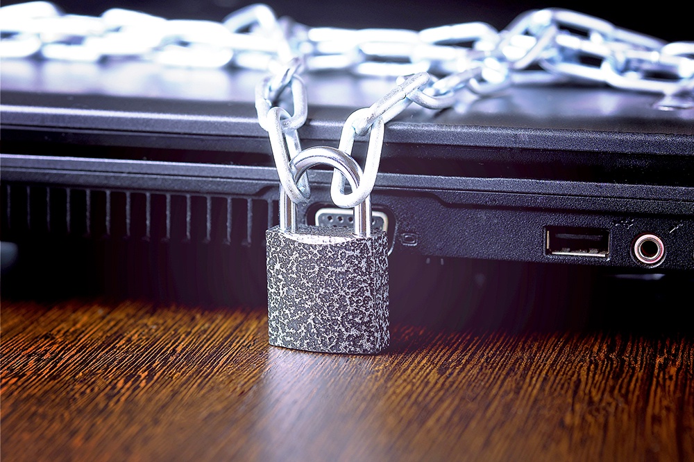 ноутбук с цепью и замком лежит на столе