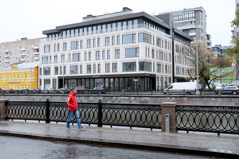 мужчина идет по набережной, на заднем фоне клубный дом