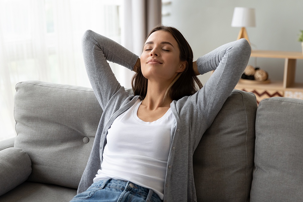 Девушка сидит на диване закрыв глаза