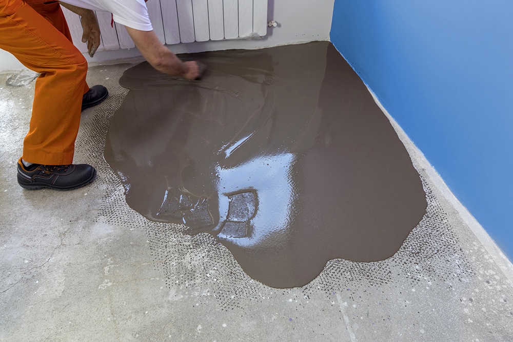 мужчина разравнивает наливной пол инструментом