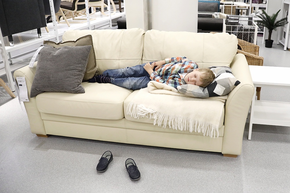 Мальчик спит на диванев магазине