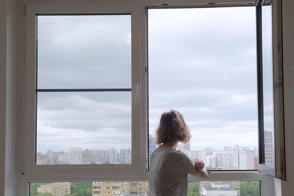 Женщина смотрит в окно.