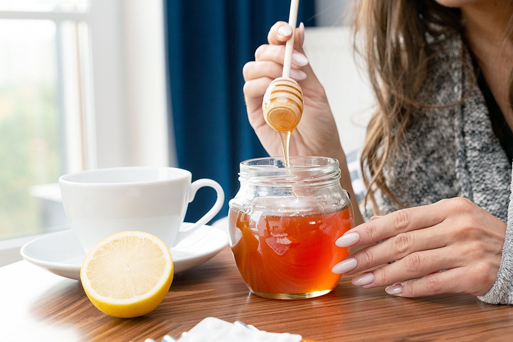 женские руки держат деревянную палочку с медом