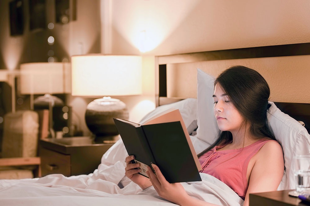 женщина читает книгу сидя в кровати