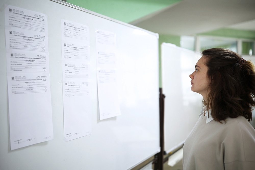Девушка смотрит доску с результатами ЕГЭ