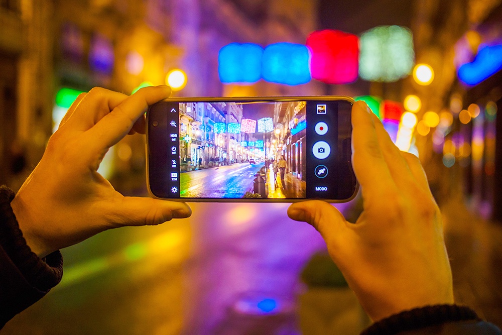 мужчина фотографирует ярко освещенную улицу