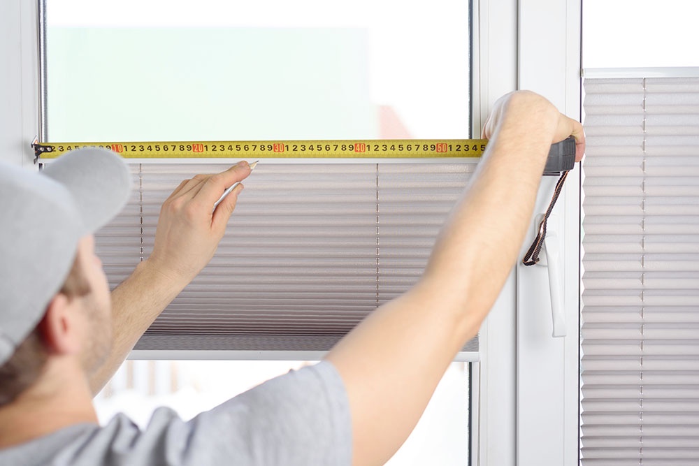 мужчина делает замеры окна рулеткой