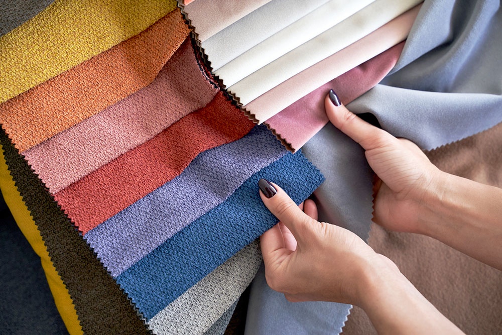 женские руки трогают текстуру материала на образцах ткани