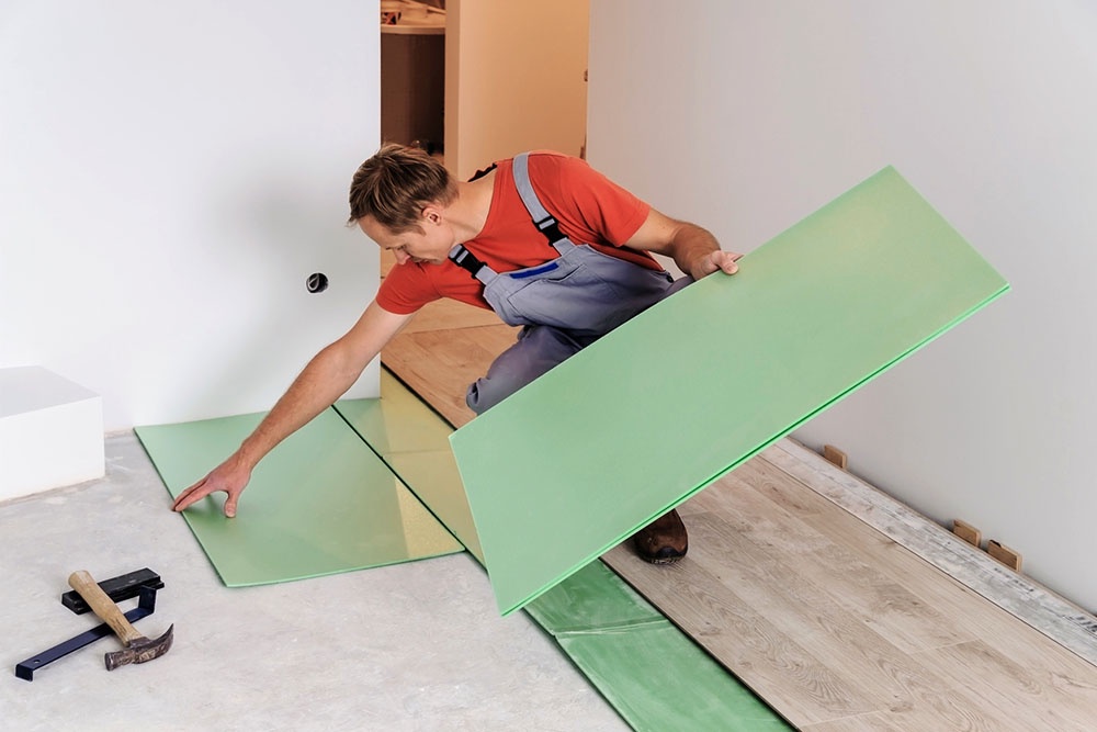 Мастер укладывает подложку для ламината на бетонный пол