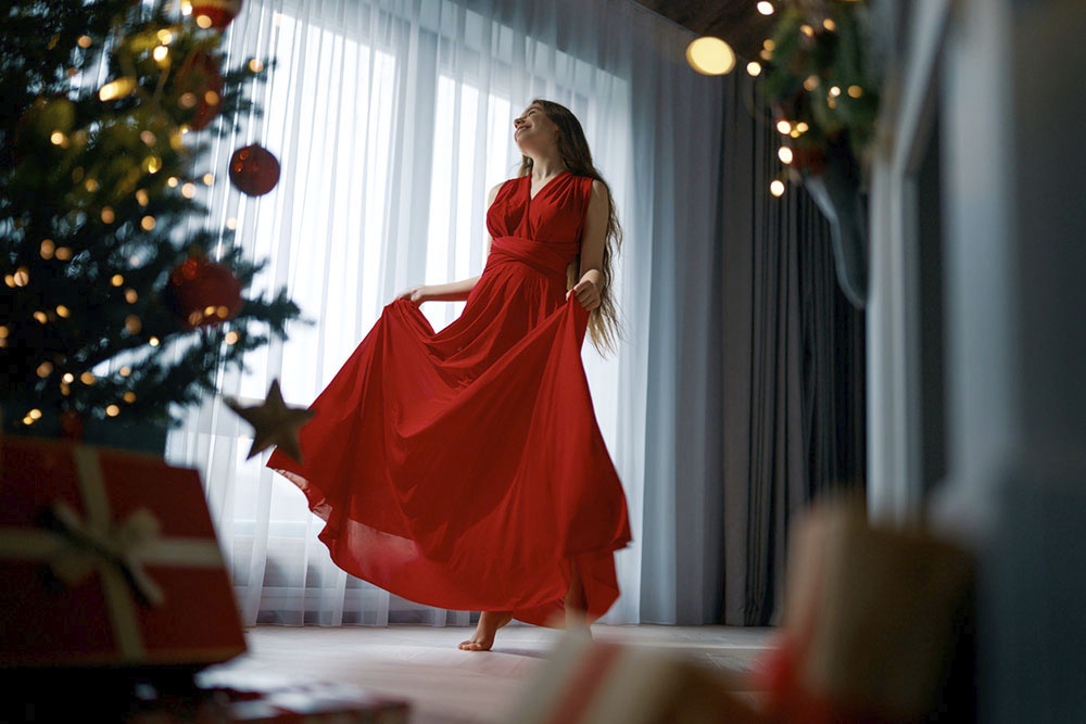 Девушка украшает елку в красном платье