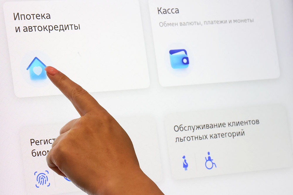 Человек выбирает раздел ипотека на терминале в банке