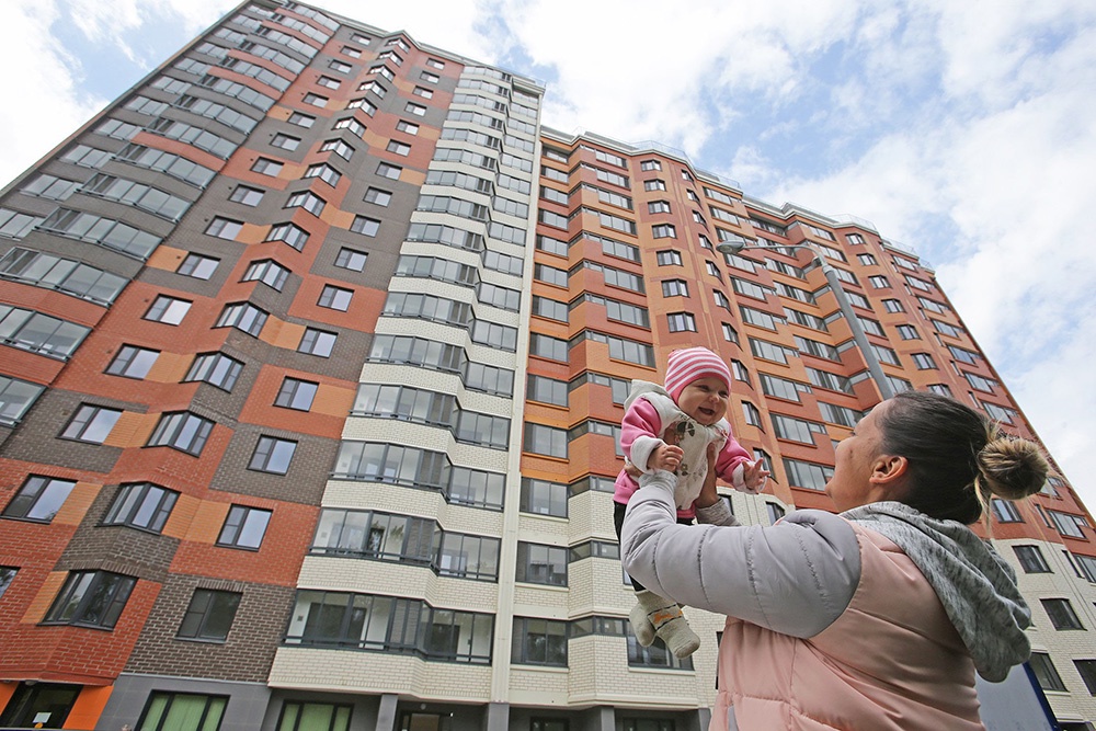 Счастливая мать и ребенок на фоне нового дома