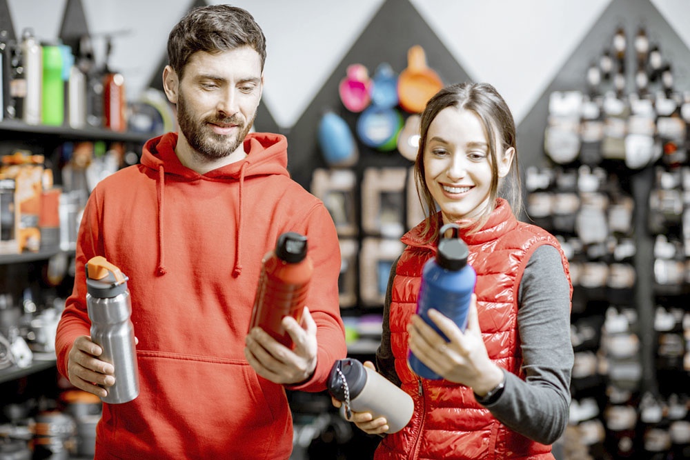 Девушка и мужчина выбирают термос и термокружку  в магазине