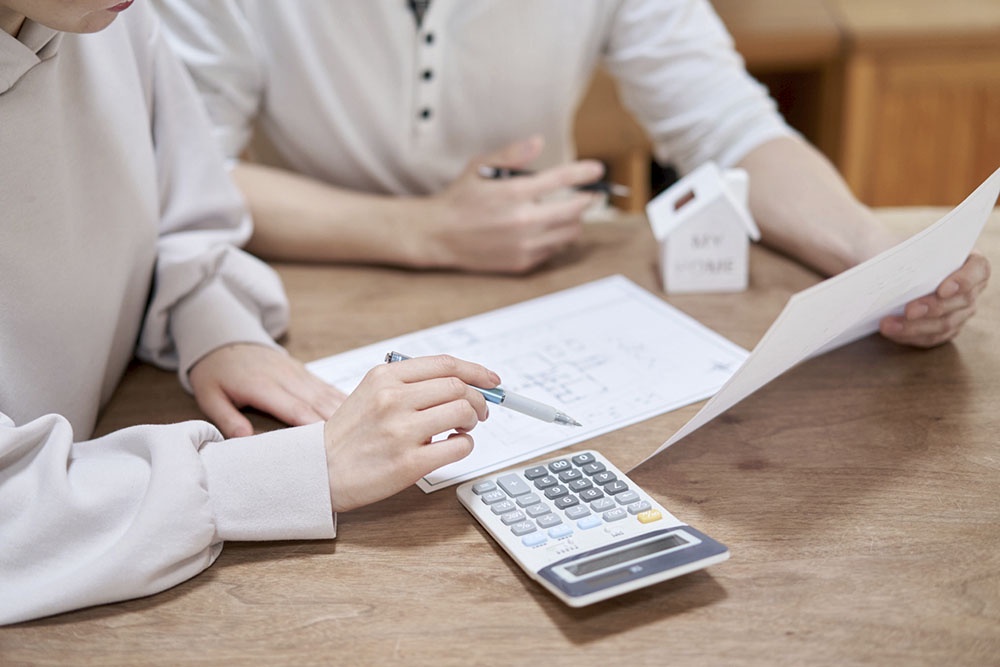 Мужчина и женщина рассчитывают на калькуляторе расходы на недвижимость
