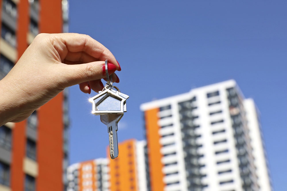 Ключи от квартиры в руке на фоне жилого комплекса
