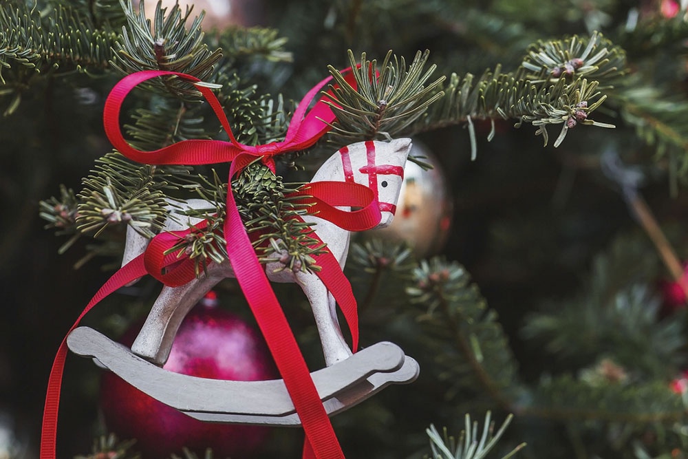 На елке висит новогодняя игрушка - лошадь