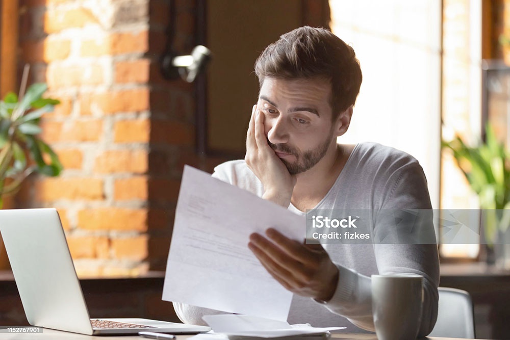 Молодой человек сидит за компьютером и изучает документы