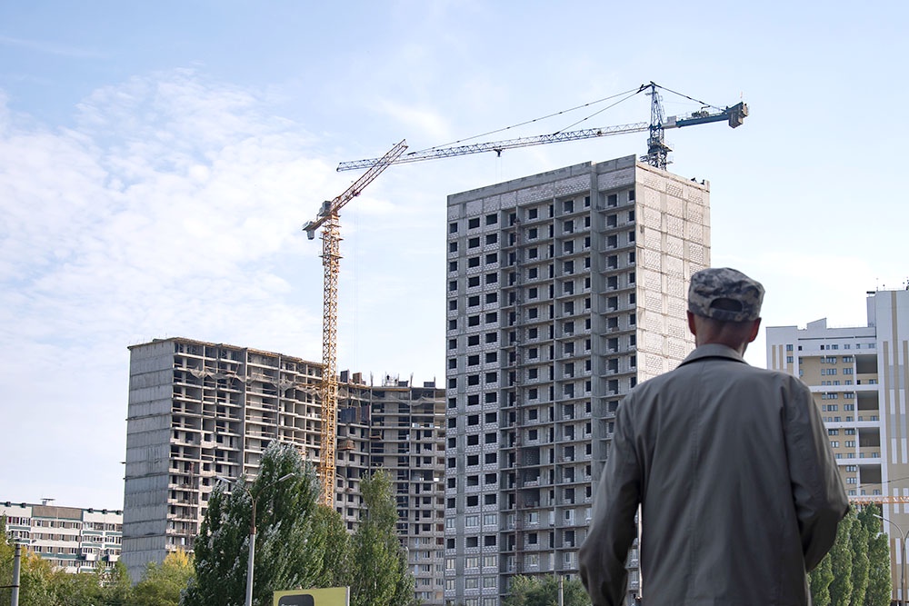 Мужчина на смотрит на строящийся дом