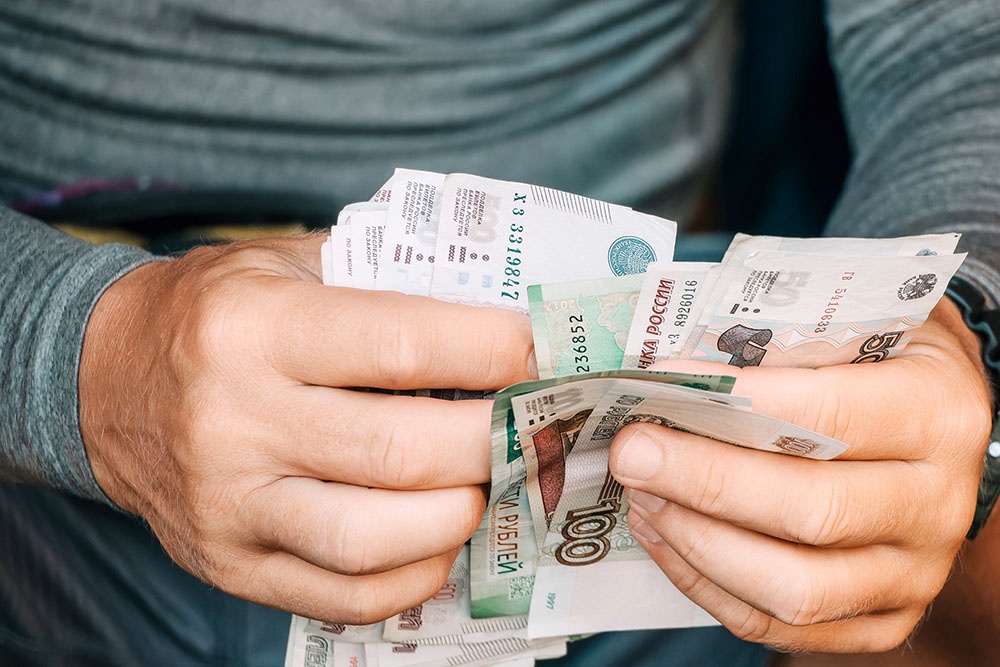 Мужчина держит в руках купюры и пересчитывает их