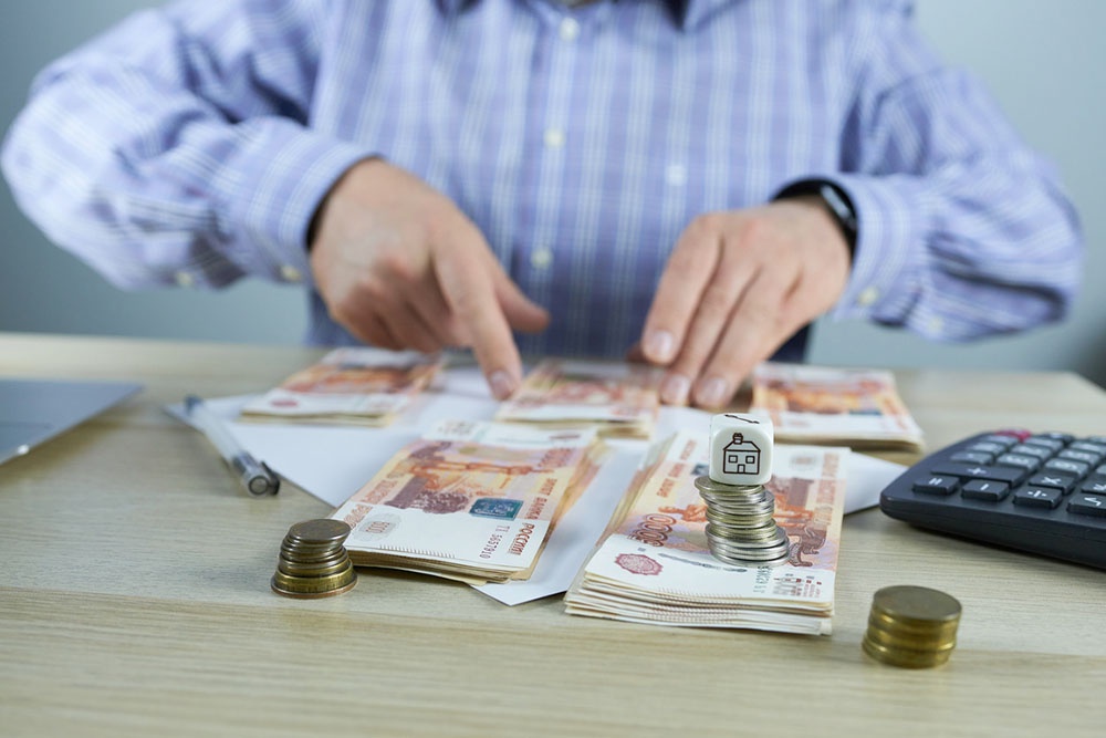 Мужчина распределяет рубли откладывая на разные траты