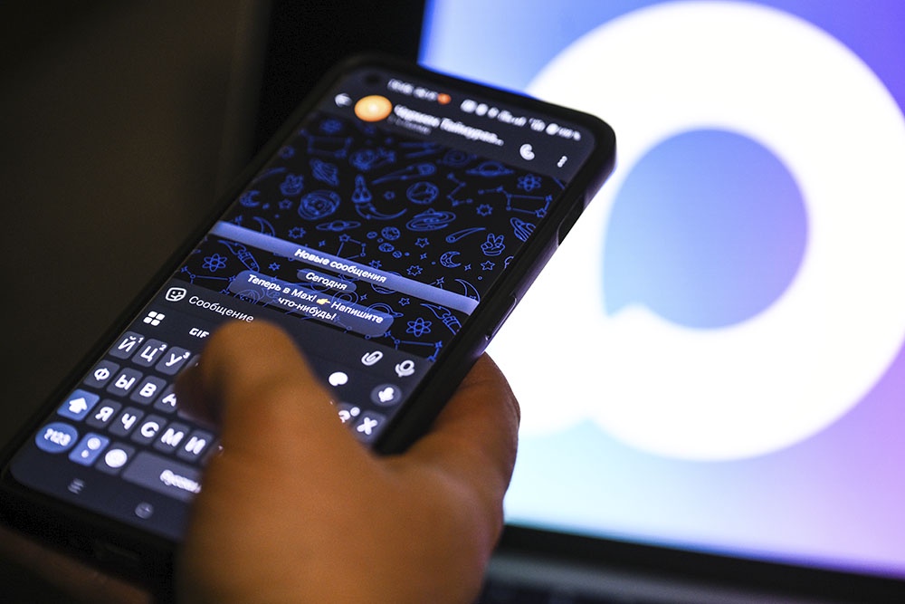 Человек держит смартфон в руке с установленным мессенджером