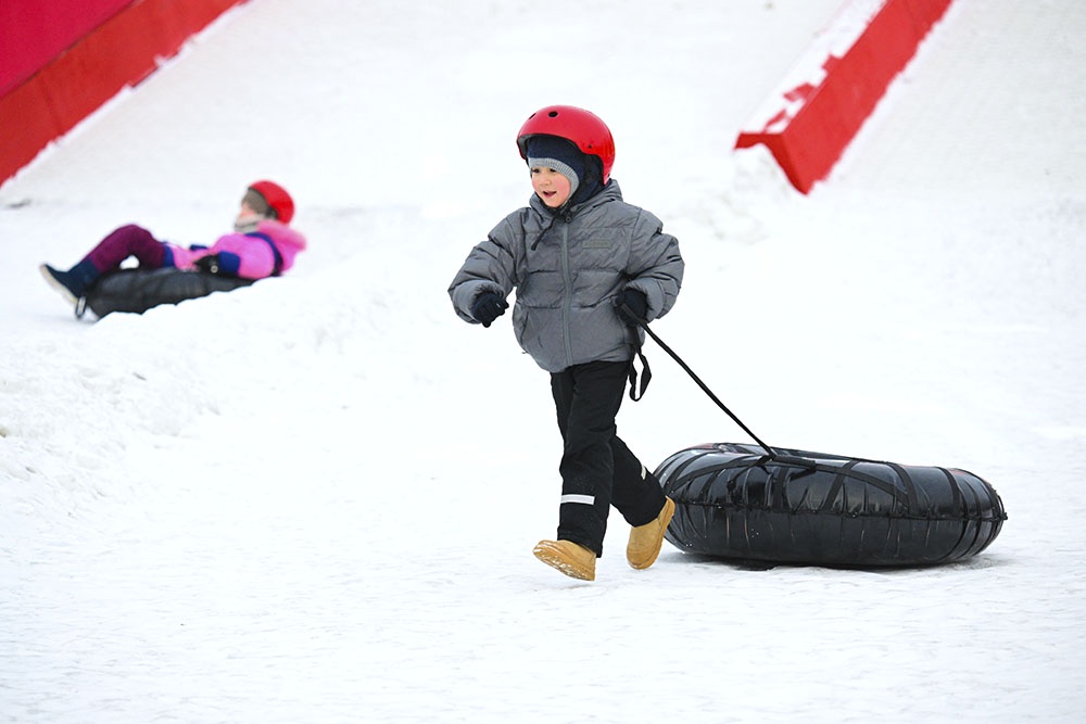 Ребенок в защитном шлеме на тюбинговой трассе