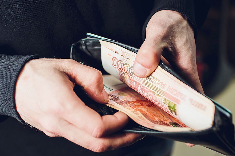 Человек пересчитывает купюры