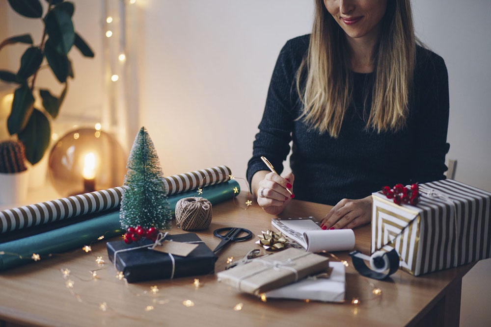 женщина упаковывает и подписывает подарки