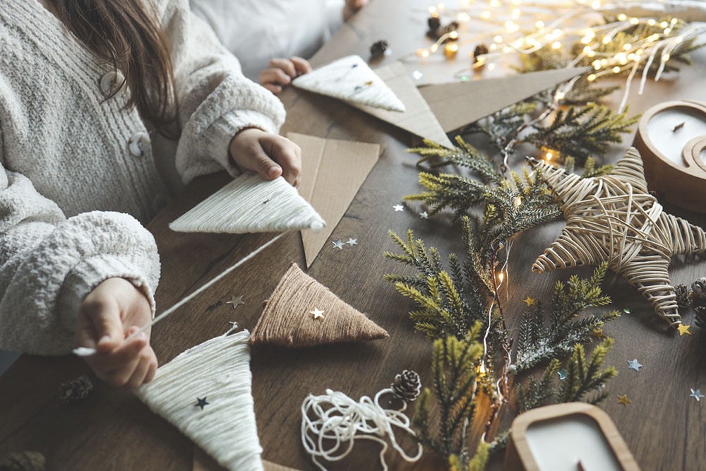 девочка делает украшение на новогоднюю елку из ниток