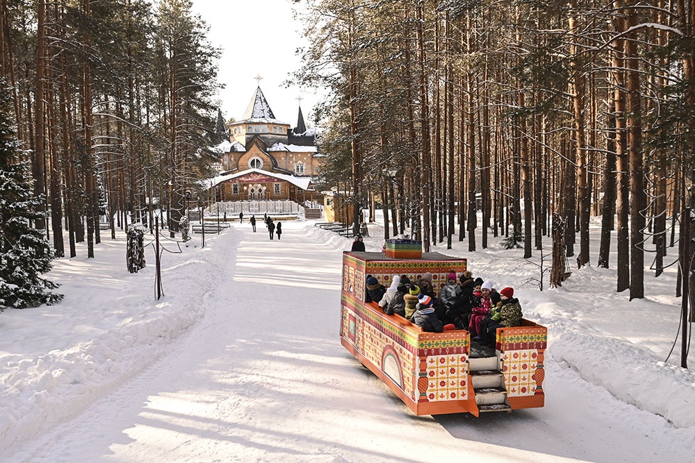Дети едут на стилизованной печи по территории вотчины Деда Мороза