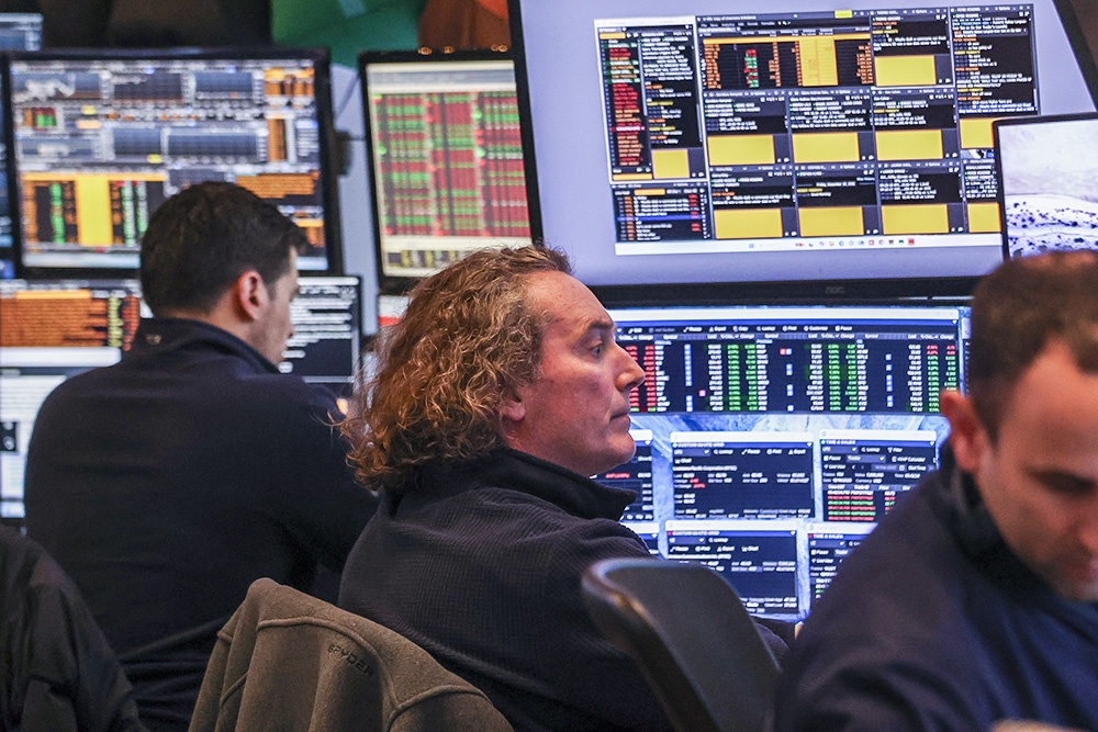 Три мужчины сидят перед множеством экранов компьютеров.