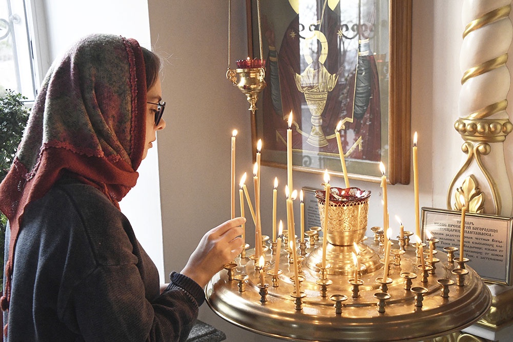 женщина в храме ставит свечку