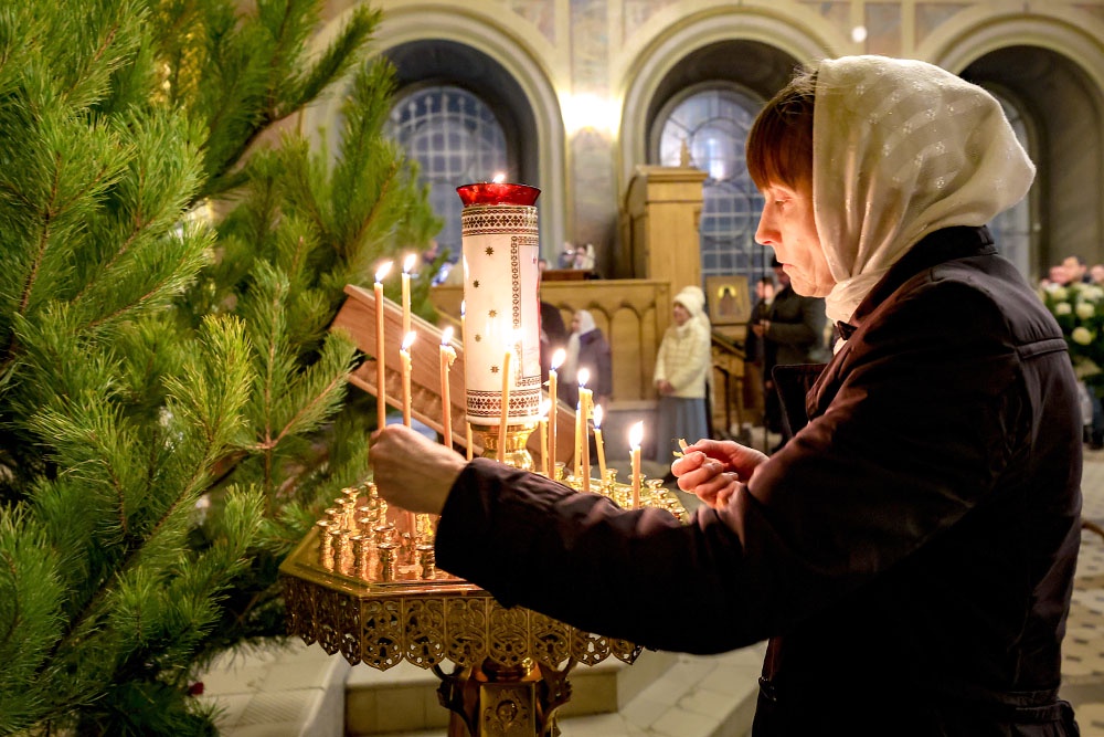 женщина в храме ставит свечку
