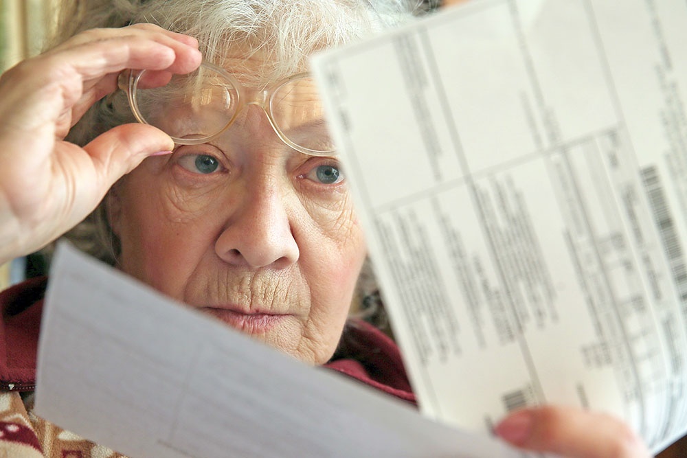 Пенсионерка проверяет счета за коммунальные услуги