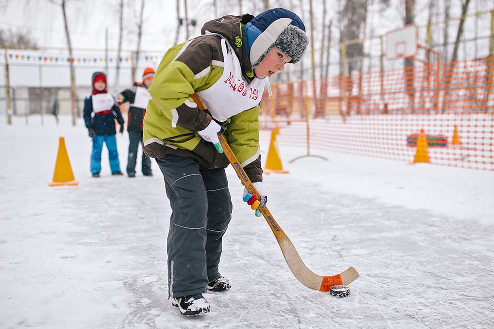 Дети участвуют в праздновании дня снега, играют в хоккей