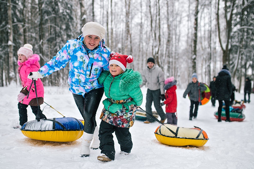 Дети и родители идут кататься на тюбингах в парк, чтобы отпраздновать день снега