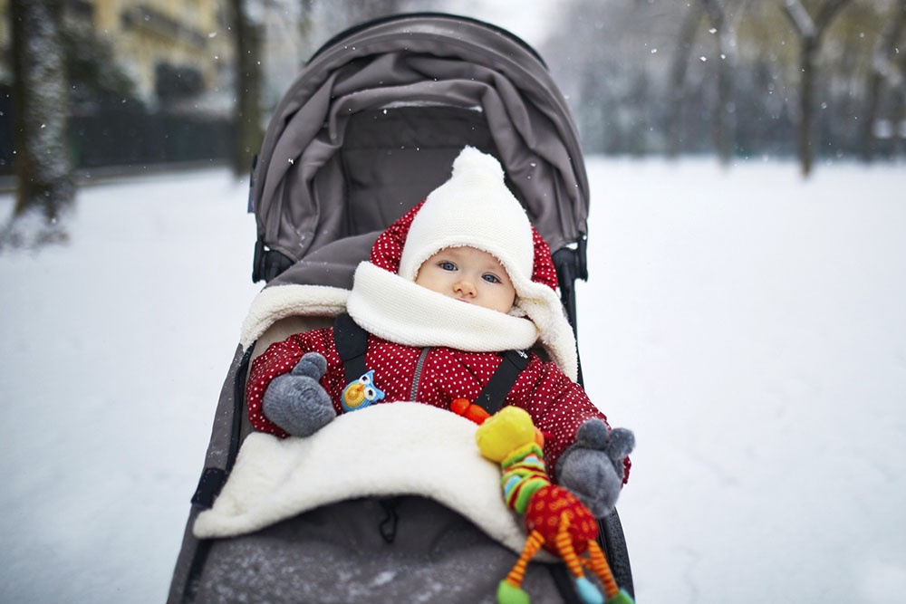 Ребенок в коляске в теплой одежде на прогулке зимой
